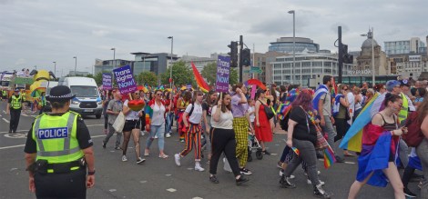 Picture of attendees at the Pride Glasgow march, some holding "Trans Rights Now" placards